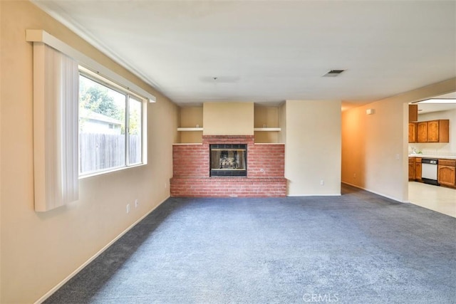 unfurnished living room featuring carpet flooring and a brick fireplace