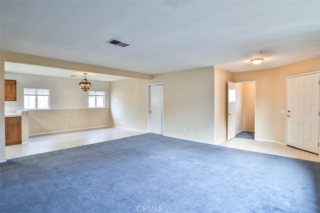 empty room with light carpet and a notable chandelier