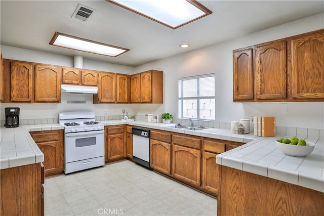 kitchen with kitchen peninsula, tile counters, white appliances, and sink