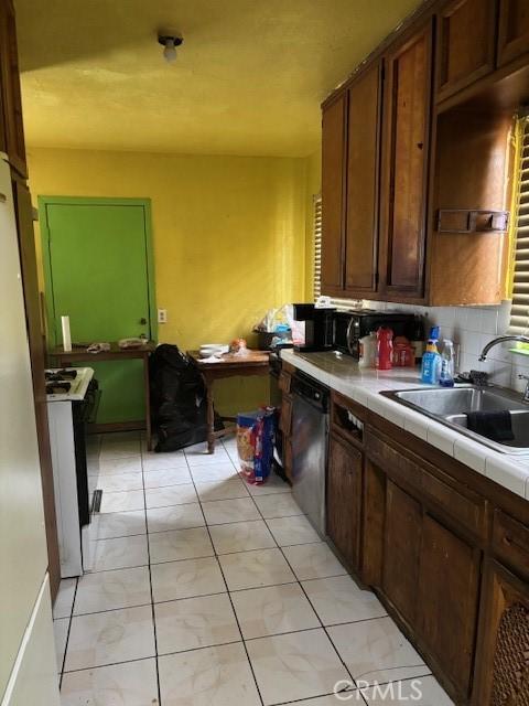 kitchen featuring dishwasher, backsplash, sink, tile counters, and dark brown cabinets