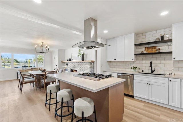 kitchen with island exhaust hood, sink, and white cabinets