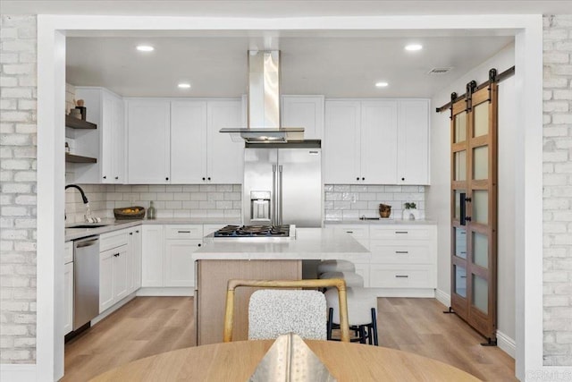 kitchen featuring white cabinets, appliances with stainless steel finishes, a barn door, and extractor fan