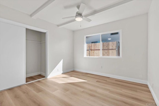 unfurnished bedroom with beamed ceiling, ceiling fan, light hardwood / wood-style floors, and a closet