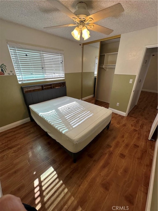 unfurnished bedroom featuring a textured ceiling, dark hardwood / wood-style floors, a closet, and ceiling fan