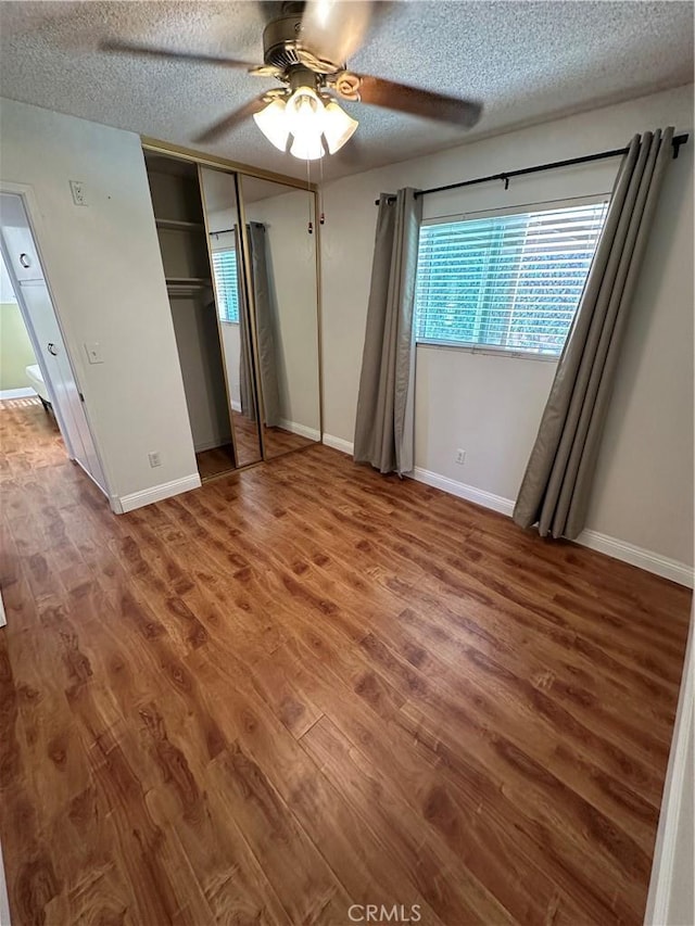 unfurnished bedroom with ceiling fan, a closet, wood-type flooring, and a textured ceiling