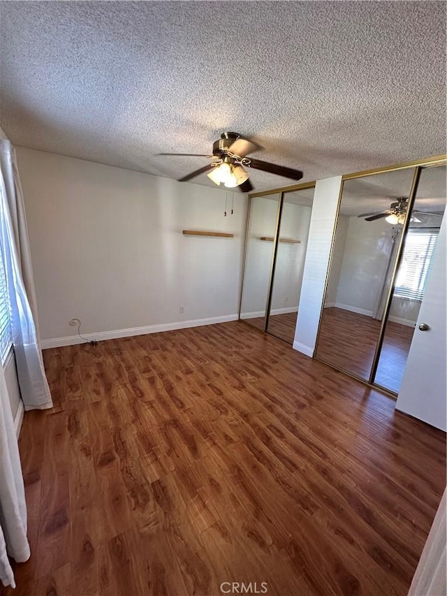 unfurnished bedroom featuring a textured ceiling, two closets, ceiling fan, and dark hardwood / wood-style floors