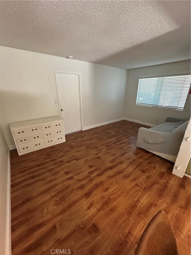 additional living space featuring dark hardwood / wood-style flooring and a textured ceiling