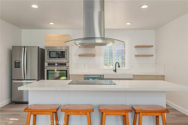 kitchen featuring a kitchen breakfast bar, sink, stainless steel appliances, and island range hood