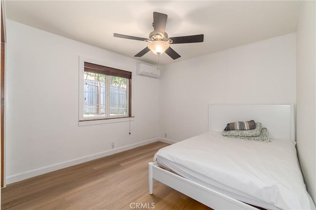 bedroom featuring a wall mounted air conditioner, light hardwood / wood-style flooring, and ceiling fan