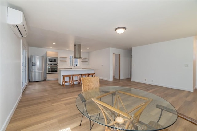 dining space featuring an AC wall unit, sink, and light hardwood / wood-style floors