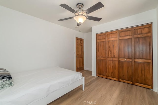 bedroom featuring ceiling fan, a closet, and light wood-type flooring