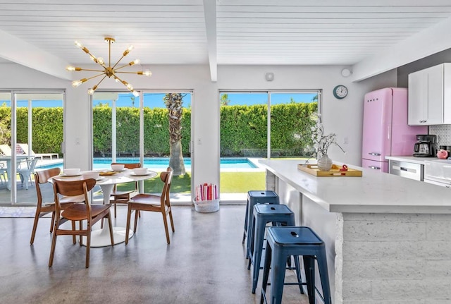 interior space featuring concrete flooring, beam ceiling, a chandelier, and a wealth of natural light