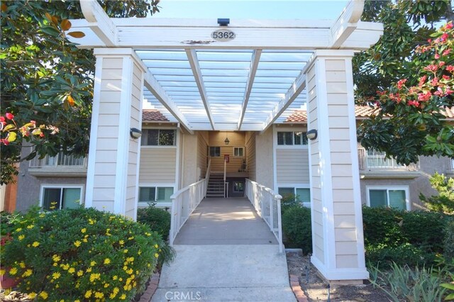 view of exterior entry with a pergola and a chimney