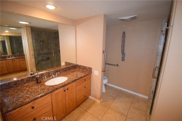 bathroom with tile patterned floors, vanity, toilet, and a shower with door