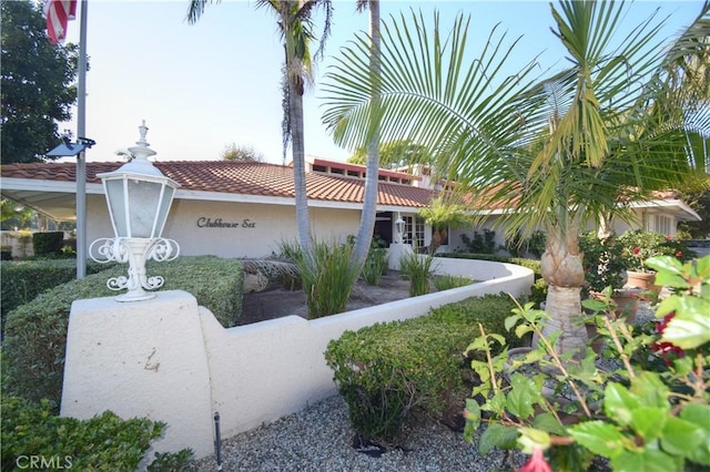 view of side of home featuring a tiled roof, a fenced front yard, and stucco siding