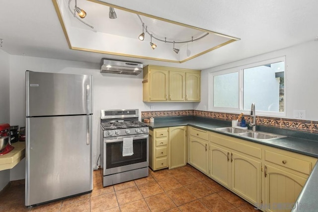 kitchen with appliances with stainless steel finishes, sink, exhaust hood, light tile patterned floors, and a raised ceiling