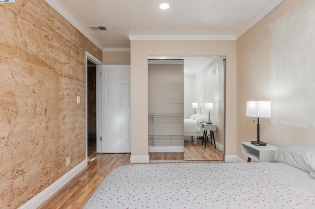 bedroom featuring a closet, ornamental molding, and hardwood / wood-style flooring