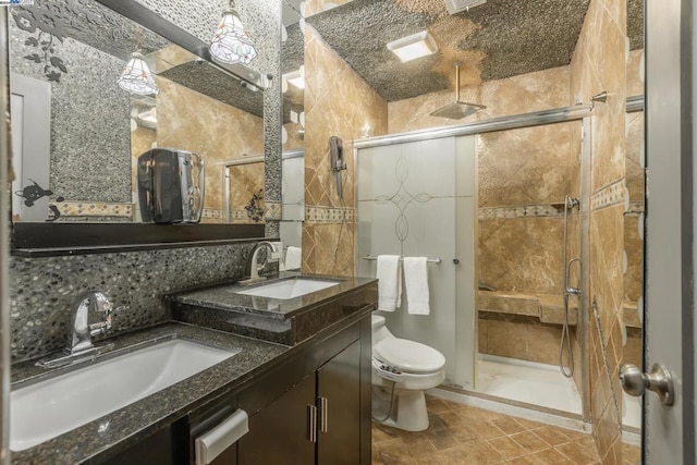 bathroom with tasteful backsplash, tile patterned flooring, toilet, a shower with door, and vanity