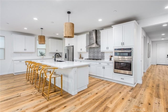 kitchen featuring white cabinetry, wall chimney range hood, and appliances with stainless steel finishes