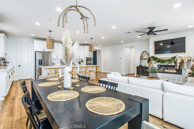 dining space with ceiling fan and light hardwood / wood-style flooring