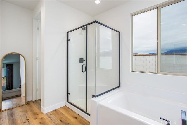 bathroom featuring plus walk in shower, a healthy amount of sunlight, and hardwood / wood-style flooring