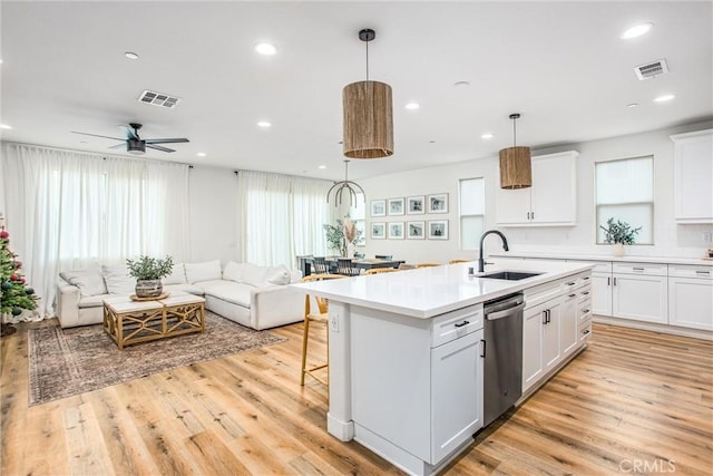 kitchen featuring white cabinets, stainless steel dishwasher, sink, and a kitchen island with sink