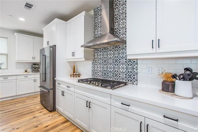 kitchen featuring white cabinetry, wall chimney exhaust hood, and appliances with stainless steel finishes