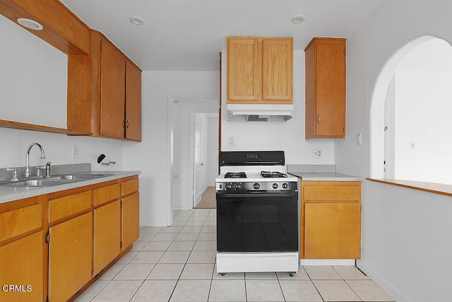 kitchen featuring white range with gas stovetop, light tile patterned floors, and sink