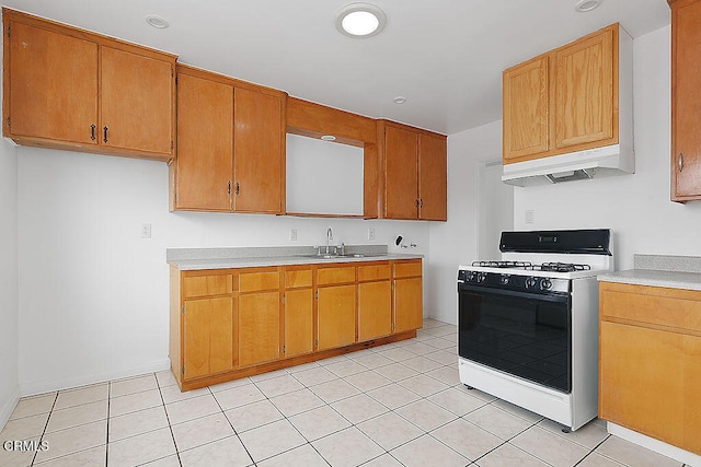 kitchen featuring white range with gas stovetop, light tile patterned floors, and sink