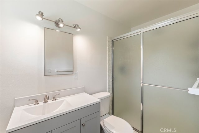 bathroom featuring toilet, vanity, and an enclosed shower