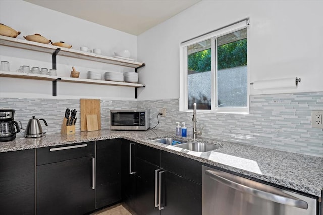 kitchen featuring decorative backsplash, stainless steel appliances, light stone counters, and sink