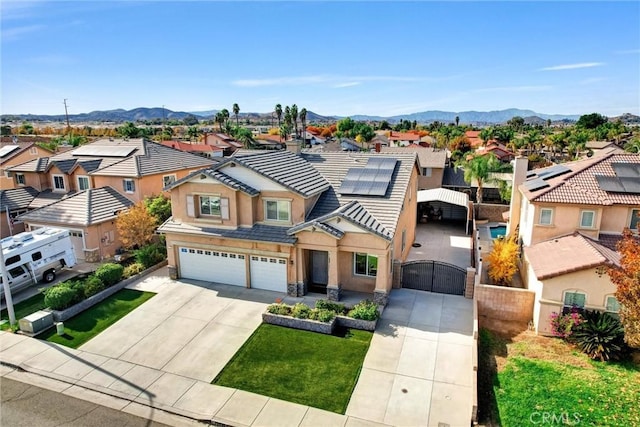 view of front of house with solar panels, a front lawn, a mountain view, and a garage