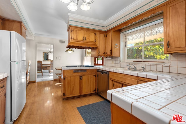 kitchen with dishwasher, plenty of natural light, white refrigerator, light hardwood / wood-style flooring, and tile counters