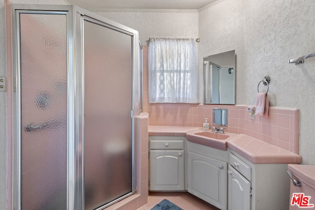 bathroom featuring decorative backsplash, tile patterned flooring, vanity, and a shower with shower door