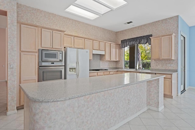 kitchen with light brown cabinets, a kitchen island, and stainless steel appliances