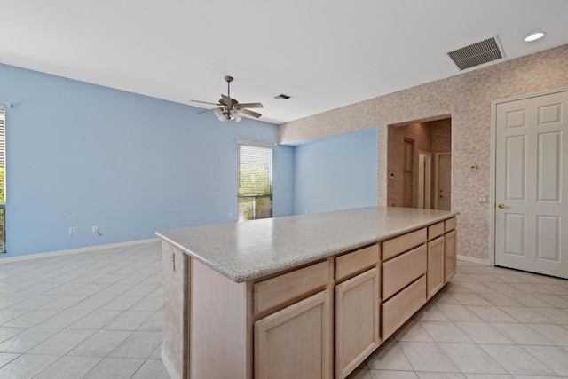 kitchen featuring ceiling fan, a kitchen island, light tile patterned floors, and light brown cabinetry