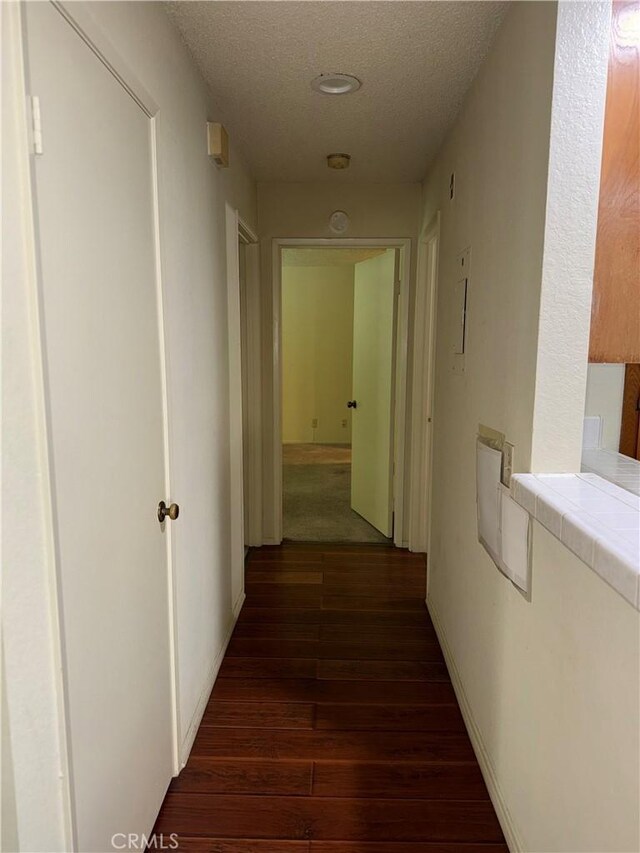 hallway featuring dark wood-type flooring and a textured ceiling