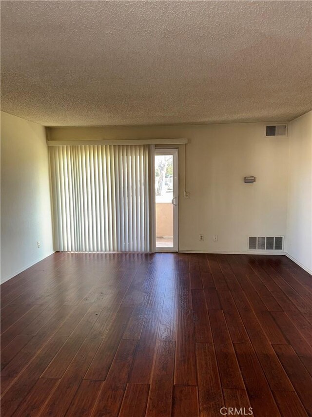 unfurnished room featuring dark wood-type flooring and a textured ceiling