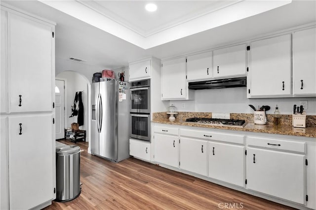 kitchen featuring appliances with stainless steel finishes, light hardwood / wood-style flooring, white cabinetry, and dark stone countertops