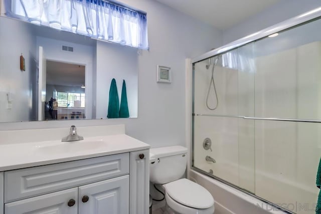 full bathroom with vanity, toilet, plenty of natural light, and enclosed tub / shower combo