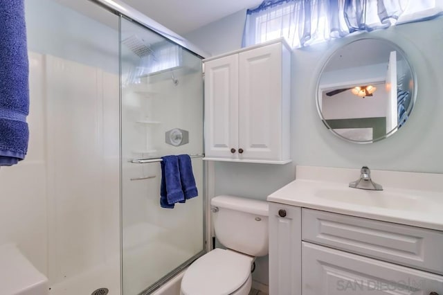 bathroom featuring a shower with door, vanity, and toilet