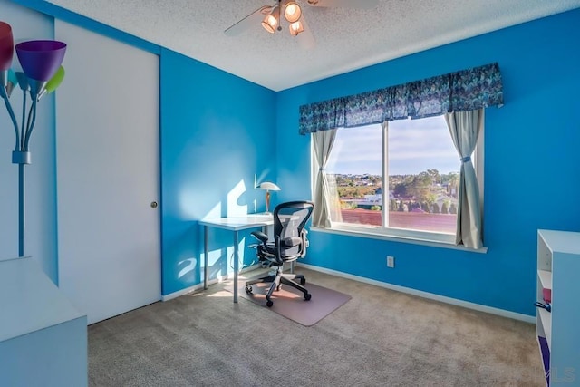 carpeted office space featuring ceiling fan and a textured ceiling