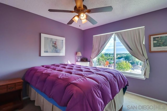 carpeted bedroom featuring ceiling fan and a textured ceiling