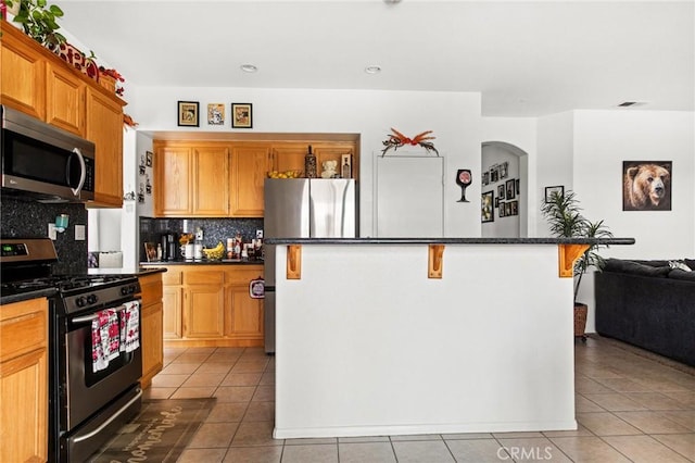 kitchen featuring a center island, stainless steel appliances, backsplash, a breakfast bar area, and light tile patterned flooring