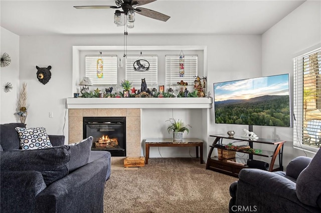 living room with carpet floors, ceiling fan, and a tiled fireplace