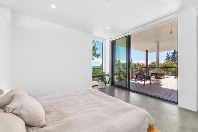 bedroom featuring a wall of windows, concrete floors, and access to outside