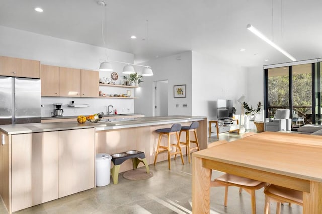 kitchen featuring expansive windows, stainless steel counters, and light brown cabinets