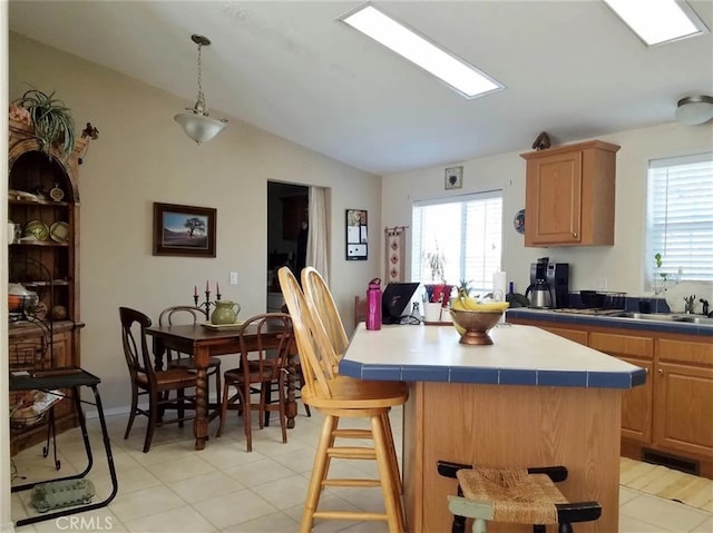 kitchen with a kitchen breakfast bar, vaulted ceiling, light tile patterned floors, tile countertops, and a kitchen island