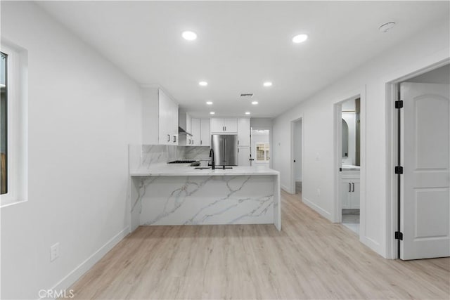 kitchen with light wood-type flooring, white cabinetry, and kitchen peninsula