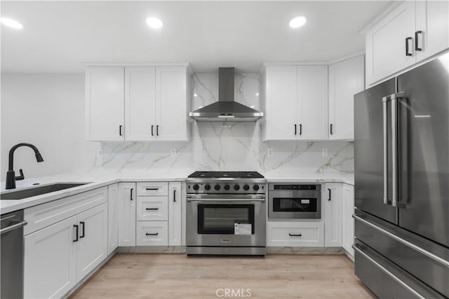 kitchen with white cabinetry, sink, wall chimney exhaust hood, and high end appliances